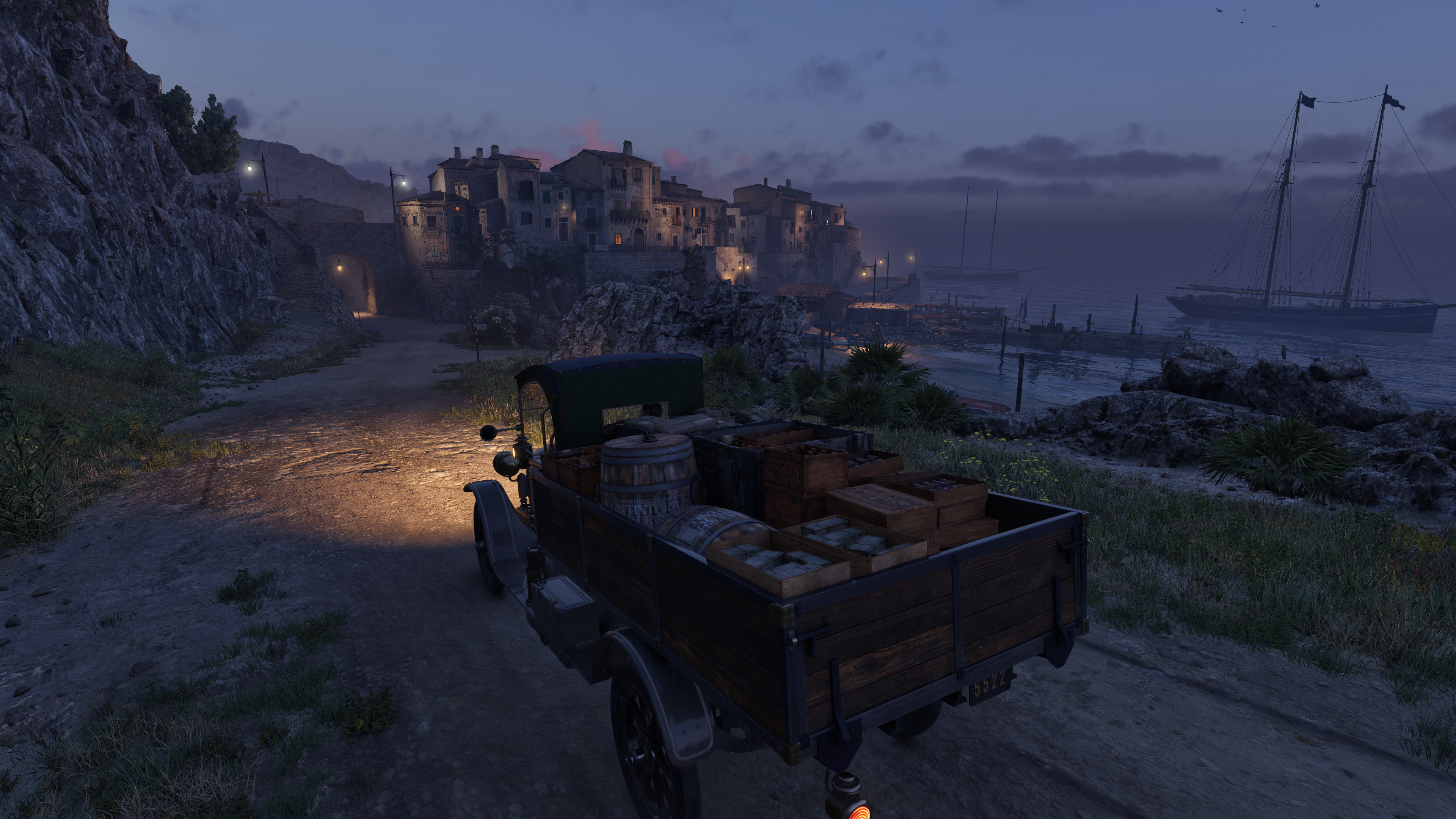 Truck on a coast road at dusk, lit port town down below